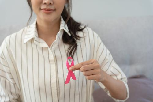 Woman in striped shirt holding tiny pink ribbon